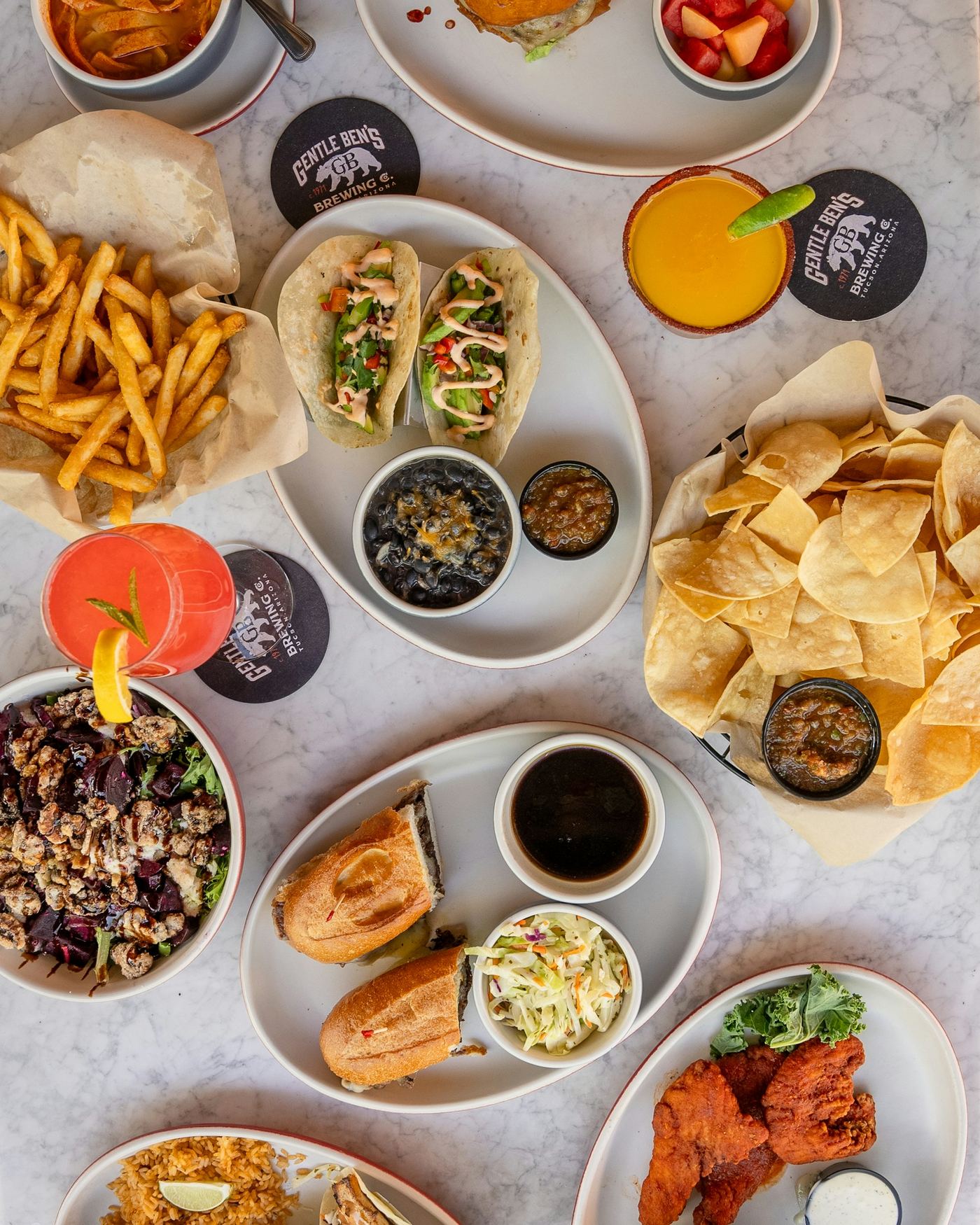 Burgers, tacos, chips and cocktails on a table at Gentle Ben's